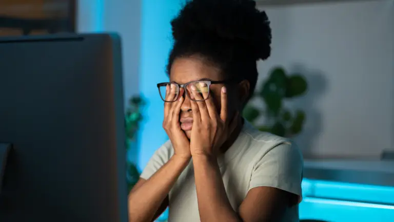 femme qui se tient la tête devant son ordinateur de travail