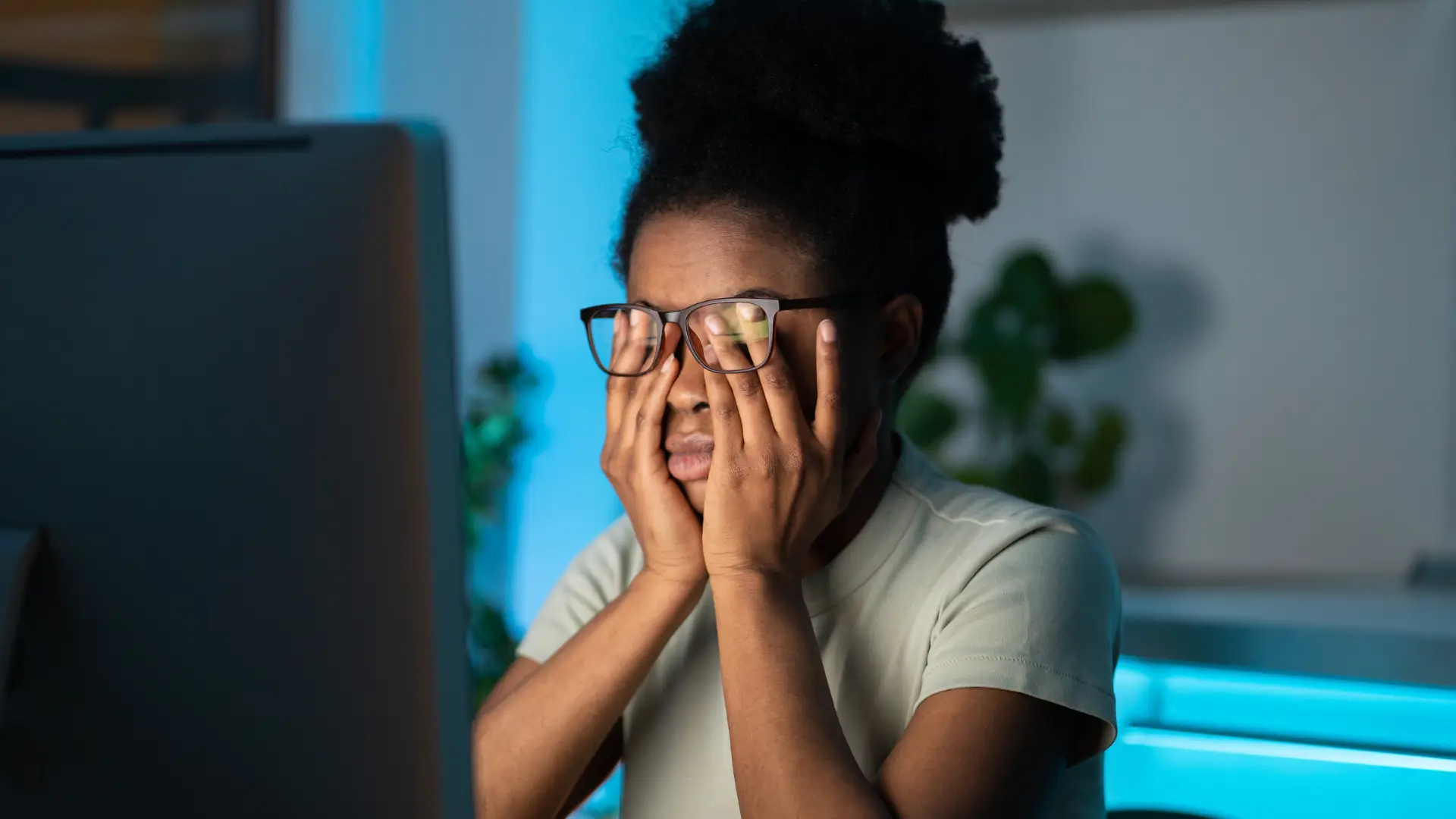 femme avec des lunettes qui se frotte les yeux devant son ordinateur de travail