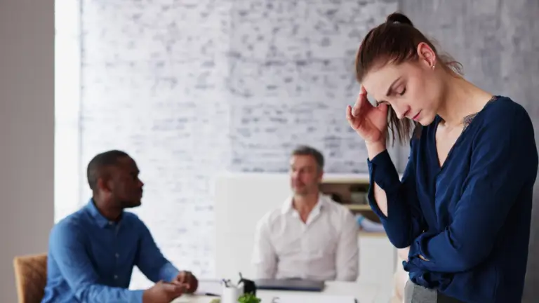 femme qui se tient la tête devant 2 hommes au bureau